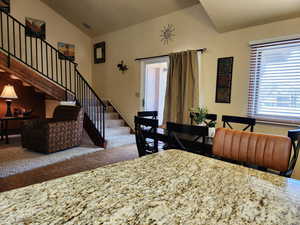 Dining area featuring lofted ceiling, visible vents, baseboards, stairs, and tile patterned floors