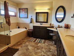 Bathroom with stone finish floor, a garden tub, vanity, and a shower stall