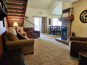 Living area featuring light carpet, stairway, and a tile fireplace