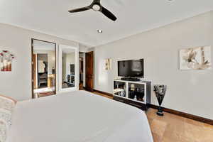 Bedroom with a ceiling fan, stone tile flooring, and baseboards