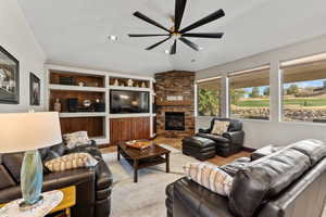 Living room with built in features, recessed lighting, visible vents, ceiling fan, and a stone fireplace