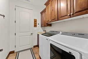 Washroom with cabinet space, washing machine and dryer, baseboards, and a sink