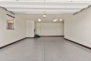 Garage featuring a garage door opener and baseboards