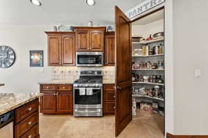 Kitchen featuring open shelves, light stone countertops, tasteful backsplash, and stainless steel appliances