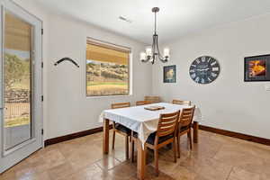 Dining area with a chandelier, baseboards, visible vents, and stone tile floors