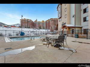 Pool featuring a patio area, a community pool, fence, and a mountain view