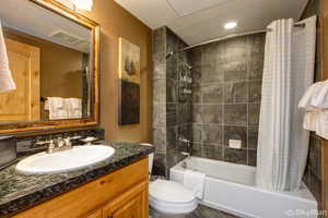 Bathroom 1 with a textured wall, toilet, shower / tub combo, vanity