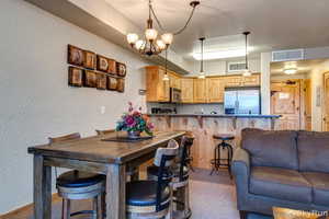 Kitchen with visible vents, appliances with stainless steel finishes, open floor plan, a peninsula, and light brown cabinetry