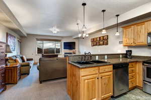 Kitchen featuring stainless steel range with electric stovetop, pendant lighting, open floor plan, and a sink