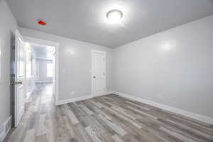 Unfurnished bedroom featuring light wood-style floors, baseboards, visible vents, and a textured ceiling