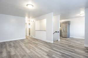 Spare room with baseboards, visible vents, a textured ceiling, and light wood finished floors