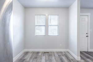 Unfurnished room featuring visible vents, light wood-style flooring, and baseboards