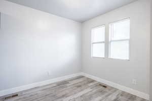 Spare room featuring light wood finished floors, baseboards, and visible vents