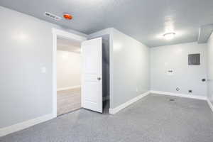 Interior space featuring laundry area, electric panel, visible vents, hookup for a washing machine, and a textured ceiling