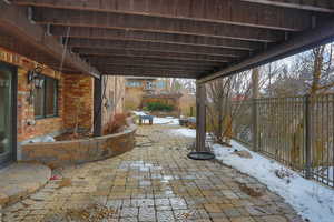 Snow covered patio with a fenced backyard and a pergola