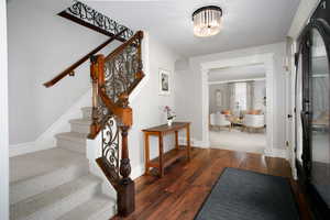 Entryway with visible vents, baseboards, stairway, dark wood finished floors, and ornate columns