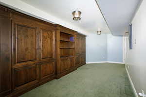 Interior space with dark carpet, a textured ceiling, and baseboards