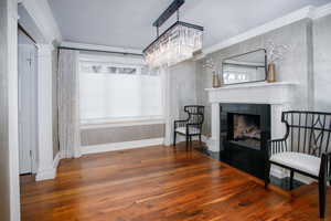 Living area with ornate columns, wood finished floors, and crown molding