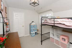 Bedroom with a textured ceiling, light colored carpet, visible vents, baseboards, and an inviting chandelier