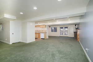 Unfurnished living room featuring dark colored carpet, french doors, and baseboards