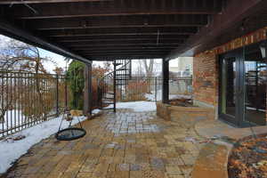 Snow covered patio featuring french doors, fence, and stairway