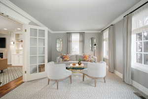 Living room featuring a fireplace, visible vents, baseboards, light wood-style floors, and crown molding