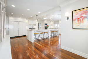 Kitchen with light stone counters, a spacious island, a sink, white cabinetry, and pendant lighting