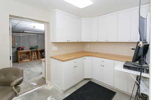 Kitchen with concrete floors, wood counters, and white cabinetry