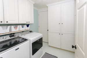 Laundry room with separate washer and dryer, cabinet space, and crown molding