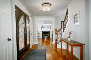 Foyer featuring an inviting chandelier, wood finished floors, french doors, and stairs