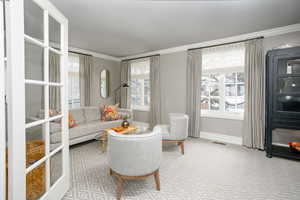 Living area with visible vents, ornamental molding, and baseboards