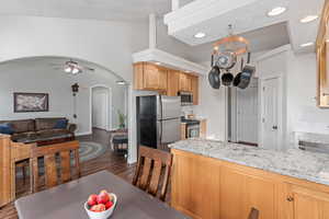 Kitchen with arched walkways, ceiling fan, stainless steel appliances, open floor plan, and decorative backsplash