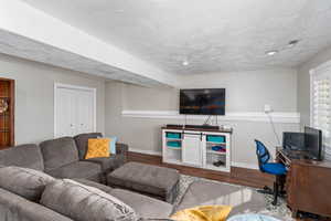 Living room with baseboards, a textured ceiling, visible vents, and wood finished floors