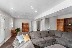 Living room featuring dark wood-style floors, stairway, baseboards, and a textured ceiling