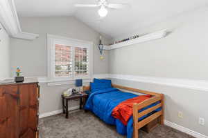 Carpeted bedroom featuring vaulted ceiling, a ceiling fan, and baseboards