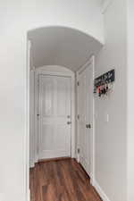 Going to garage and storage in kitchen Corridor featuring dark wood-style floors, baseboards, and arched walkways