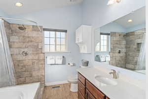 Bathroom featuring visible vents, tiled shower, toilet, wood finished floors, and vanity