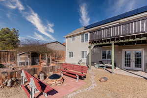 Rear view of house with a patio, an outdoor fire pit, a fenced backyard, french doors, and roof mounted solar panels