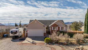 View of front facade with brick siding, concrete driveway, fence, a mountain view, and a garage