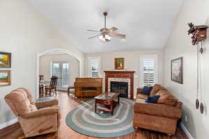 Living area with vaulted ceiling, french doors, a fireplace, and wood finished floors