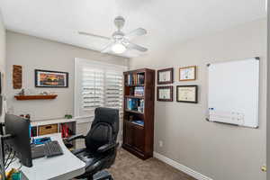 Home office/bedroom with ceiling fan, baseboards, and light colored carpet