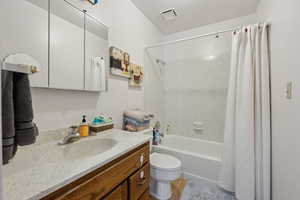 Bathroom with toilet, vanity, visible vents, and shower / tub combo with curtain