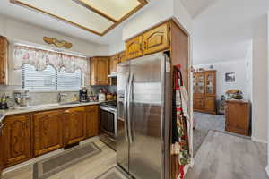 Kitchen with stainless steel appliances, brown cabinets, light countertops, and a sink