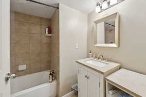 Bathroom featuring a textured ceiling, tub / shower combination, and vanity