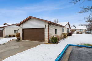 View of snow covered exterior featuring an attached garage and brick siding