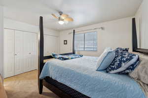 Bedroom with ceiling fan, carpet, and multiple closets