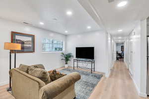 Living area featuring light wood-style flooring, baseboards, a textured ceiling, and recessed lighting