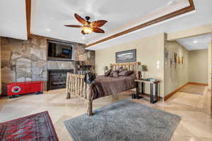 Bedroom featuring a tray ceiling, a fireplace, baseboards, and light tile patterned floors