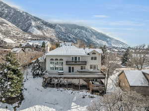 Snow covered property with a chimney, a deck with mountain view, and stucco siding