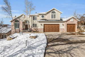 Traditional-style house with brick siding, a chimney, stucco siding, concrete driveway, and a garage